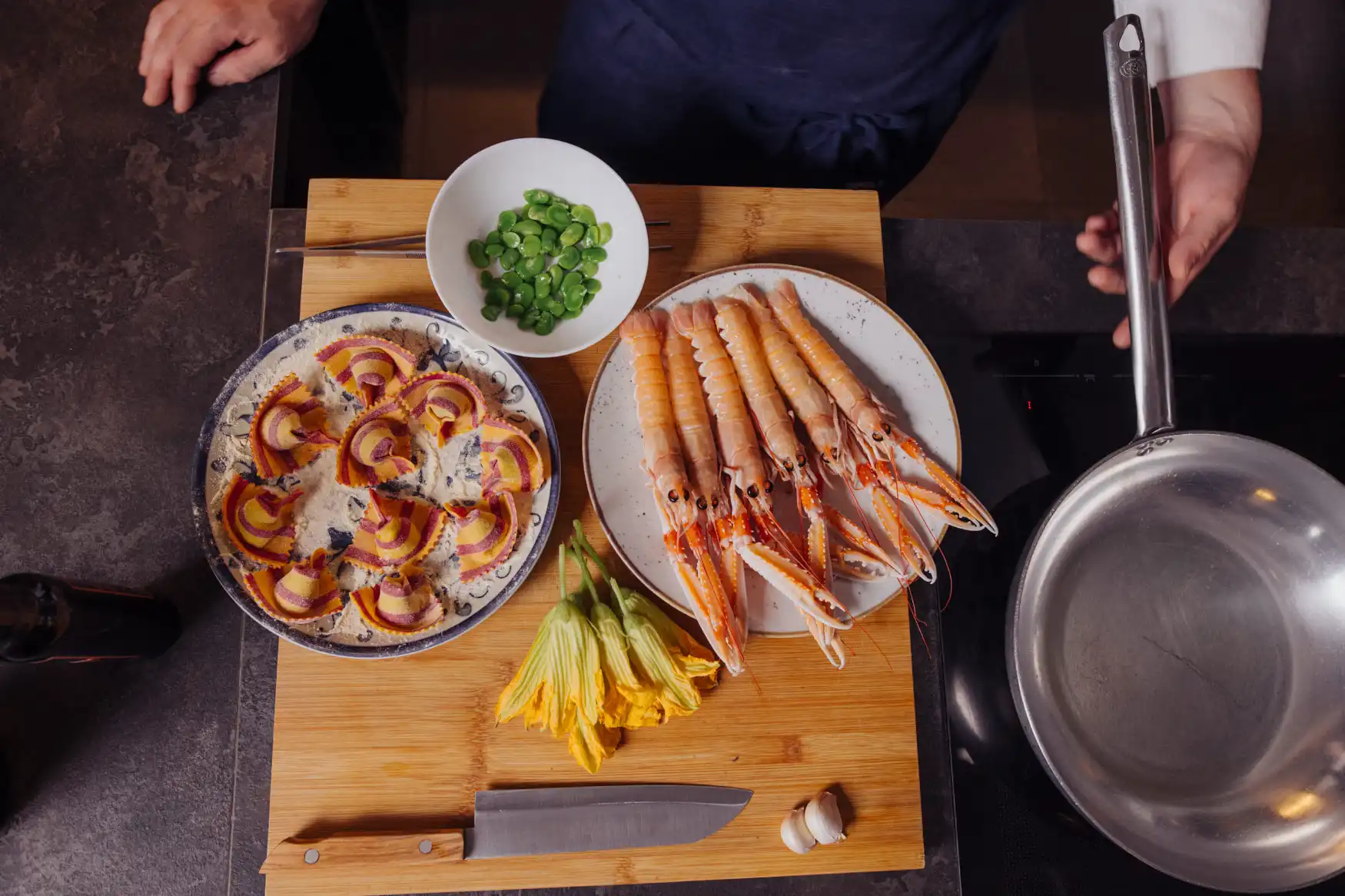 piatti con sopra scampi, ravioli fatti a mano, fiori di zucca ed edamame