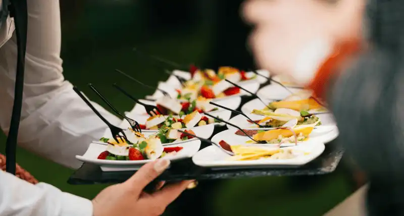 persona che porta del finger food in un piatto
