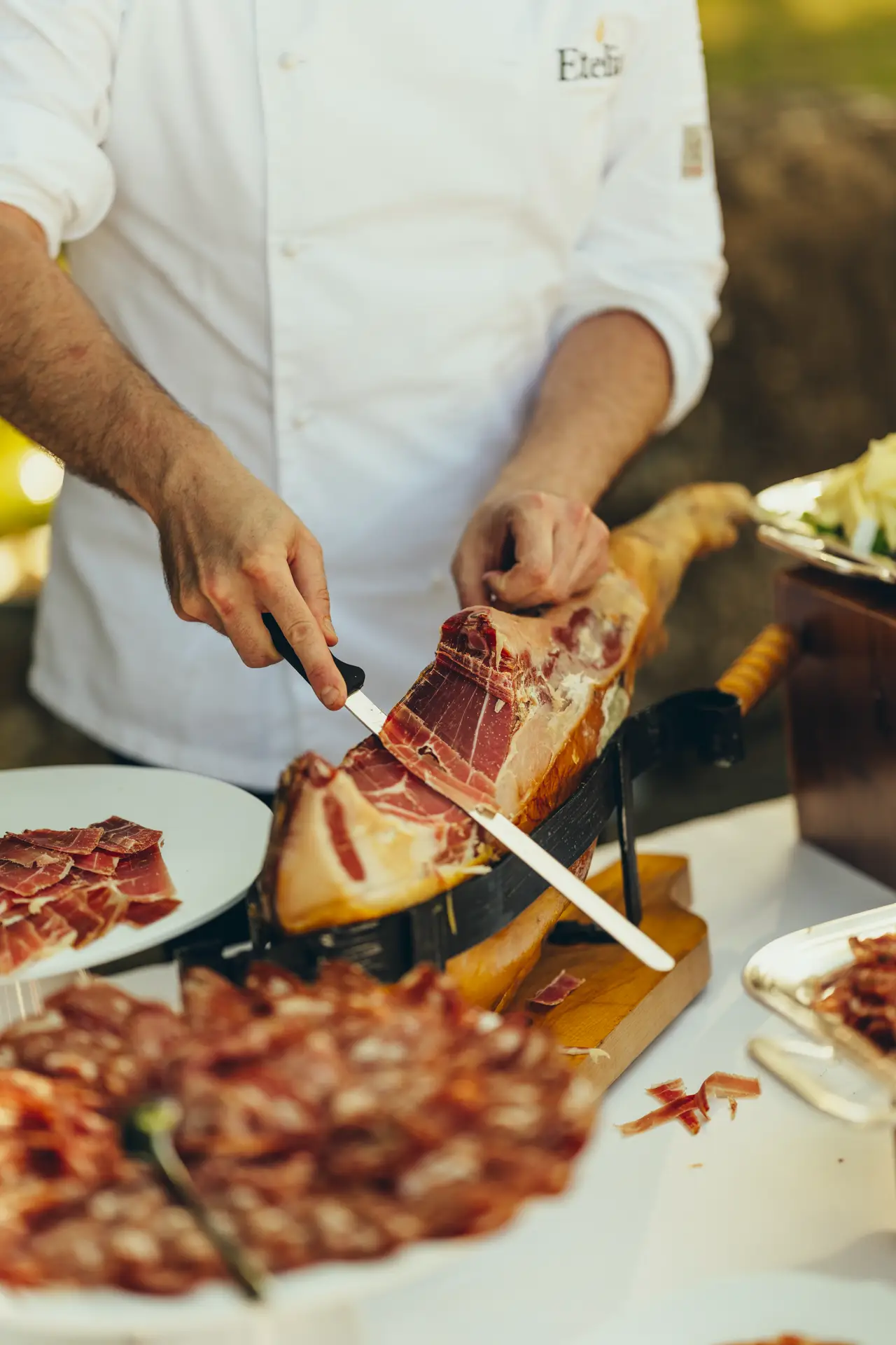 Chef hand-slicing prosciutto with a knife