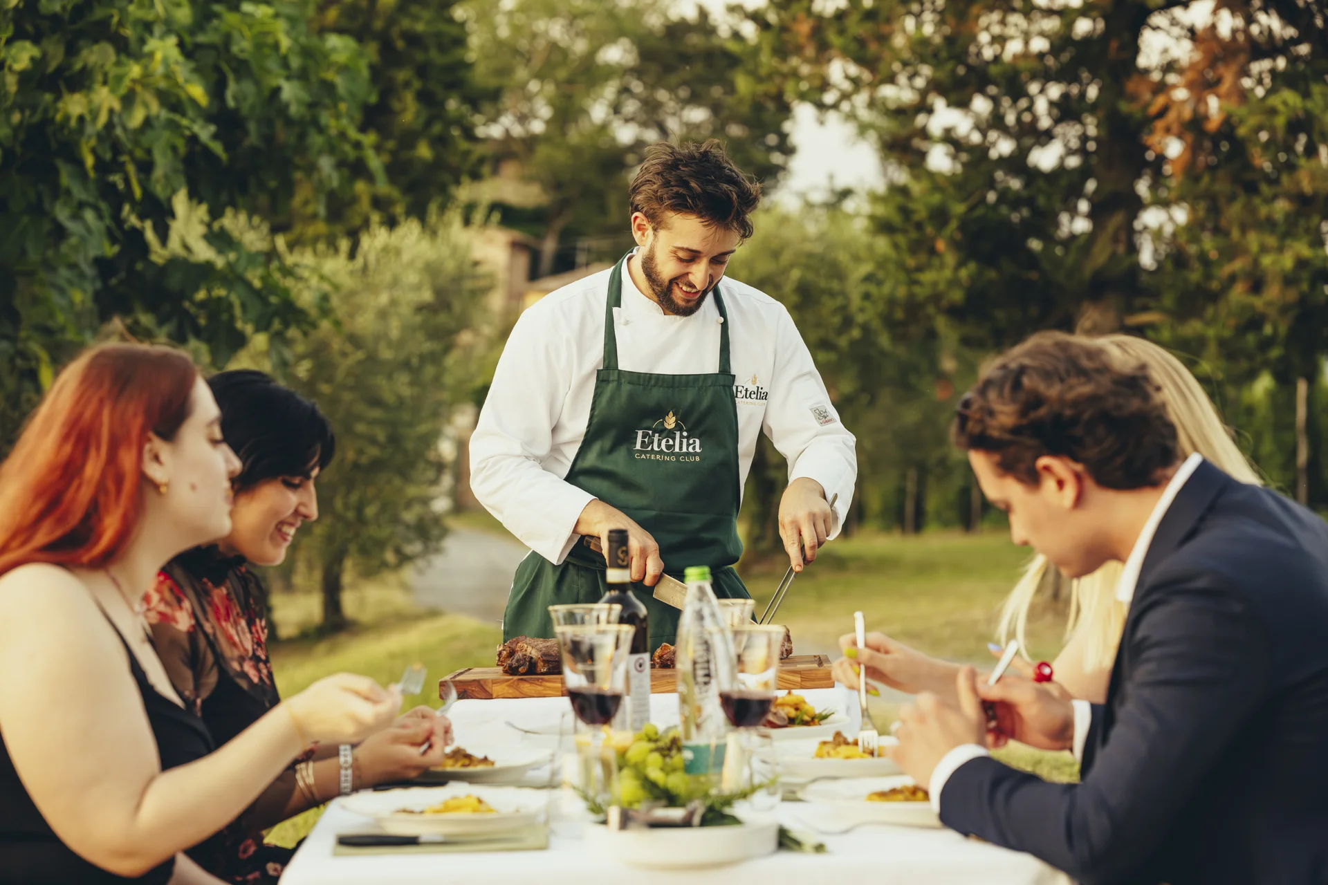 chef serving meat with people eating a meal